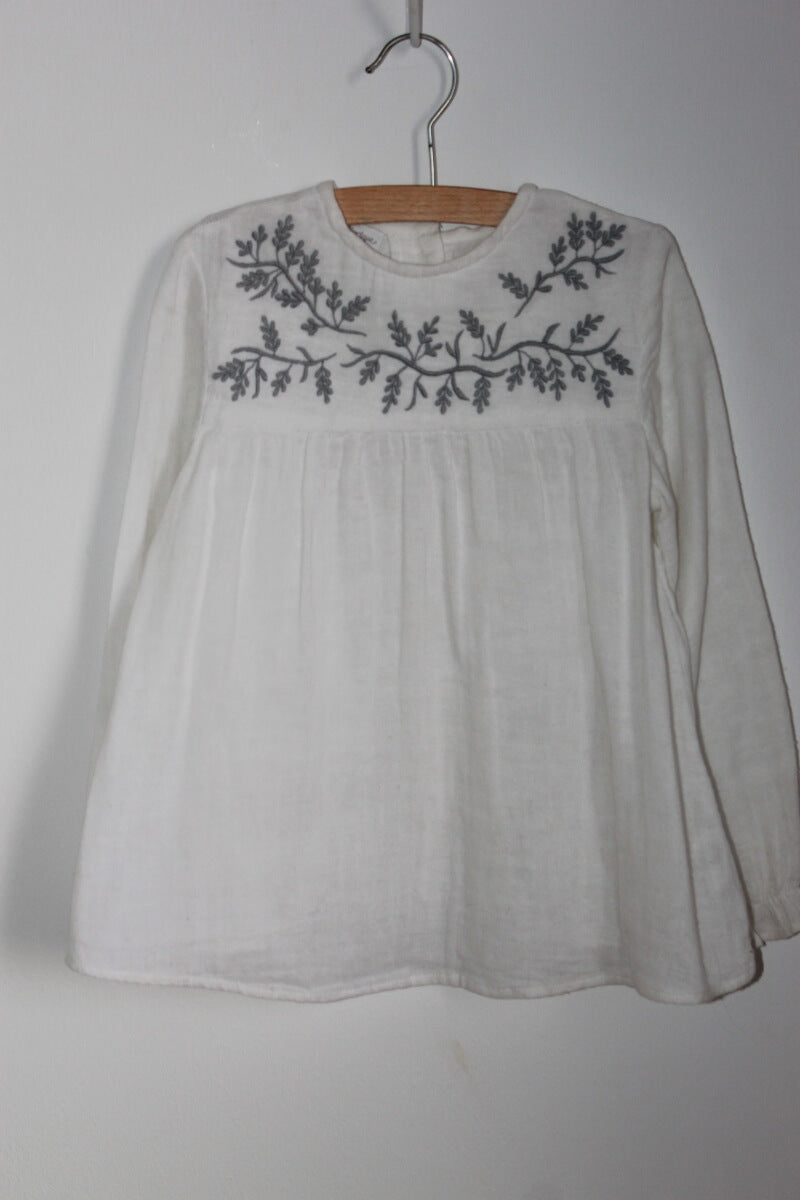 Preloved katoenen witte blouse met grijs geborduurde bloemen op de borst en lange mouwen van Fina Ejerique in maat 116 